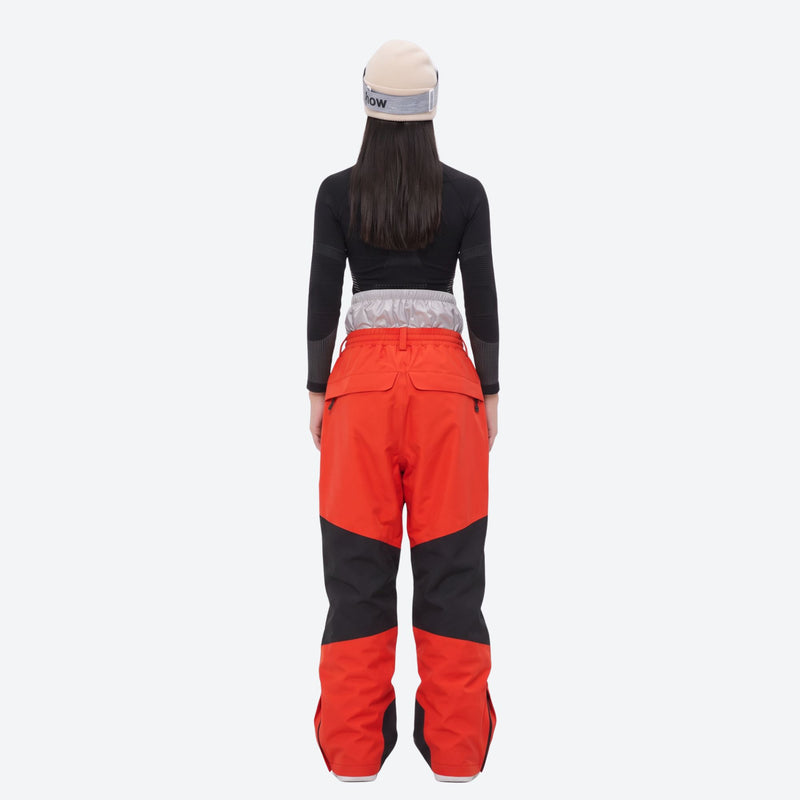 Breathable ski jacket and snow pants combo - women's orange colorblock pants with black base layer, on-model back view