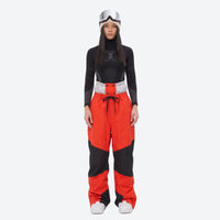 
                  
                    Colorblock snowboard jacket and pants set - women's orange colorblock pants with black base layer, on-model front view
                  
                