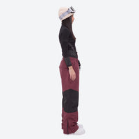 
                  
                    Breathable ski jacket and snow pants combo - women's wine colorblock pants with black base layer, on-model side view
                  
                